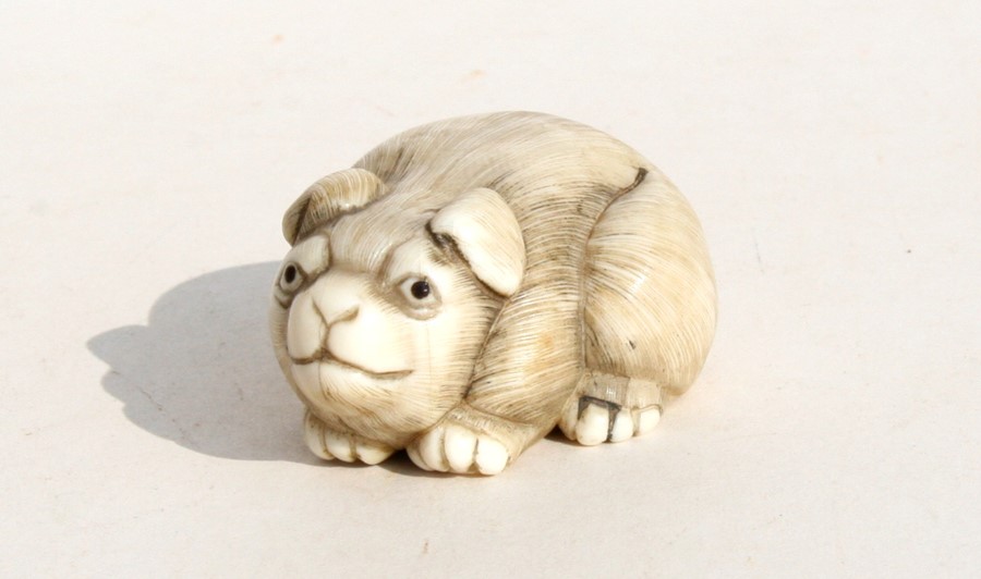 A signed Japanese ivory netsuke in the form of a puppy, 4.5cms (1.25ins) long.