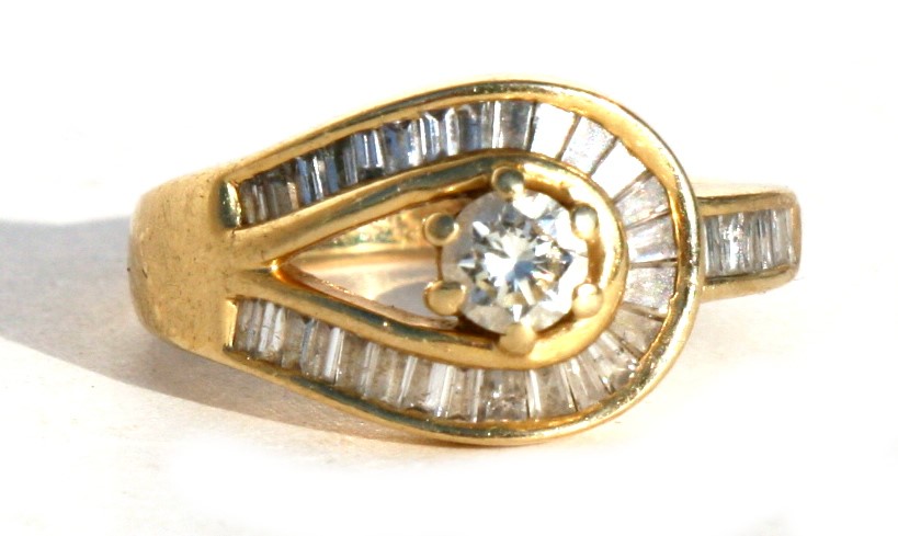 An 18ct gold diamond ring with central diamond surrounded by baguette cut diamonds, approx UK