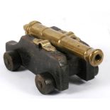 An early 20th century signal cannon with a brass barrel mounted on a wooden carriage. Barrel