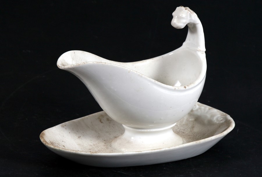 A 19th century white glazed gravy boat on stand with lion mask handle.Condition Report Good