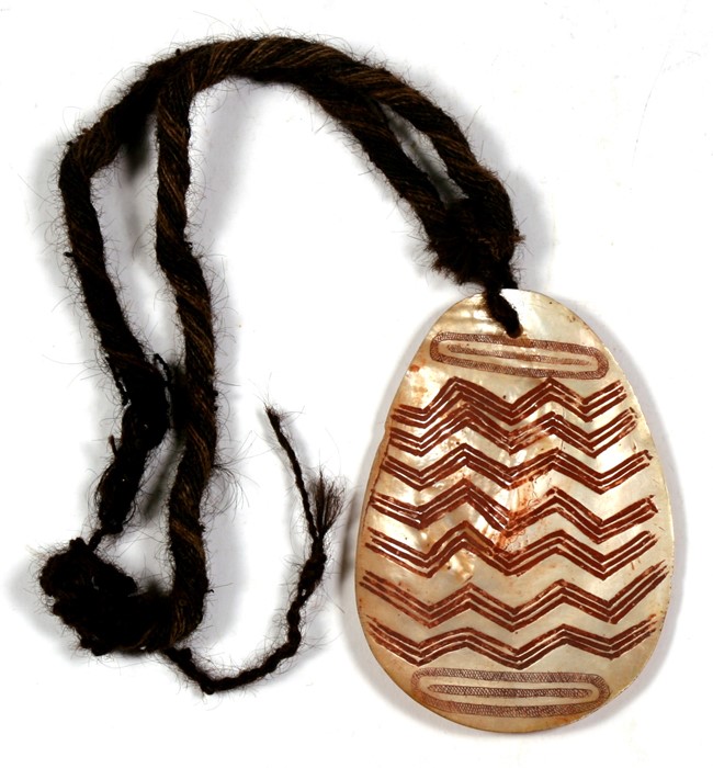 An Australian Aboriginal shell pendant with 'zig zag' design. 17cm (6.5 ins) high