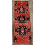 A Persian Hamadan woollen handmade runner with geometric design on a red ground, 380 by 108cms (