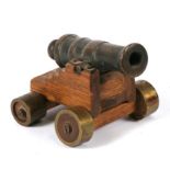 A small Victorian signal cannon with bronze barrel mounted on a wooden carriage with elevating