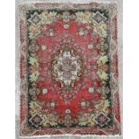 A Persian Tabriz woollen handmade rug with central foliate medallion and floral scrolls on a red