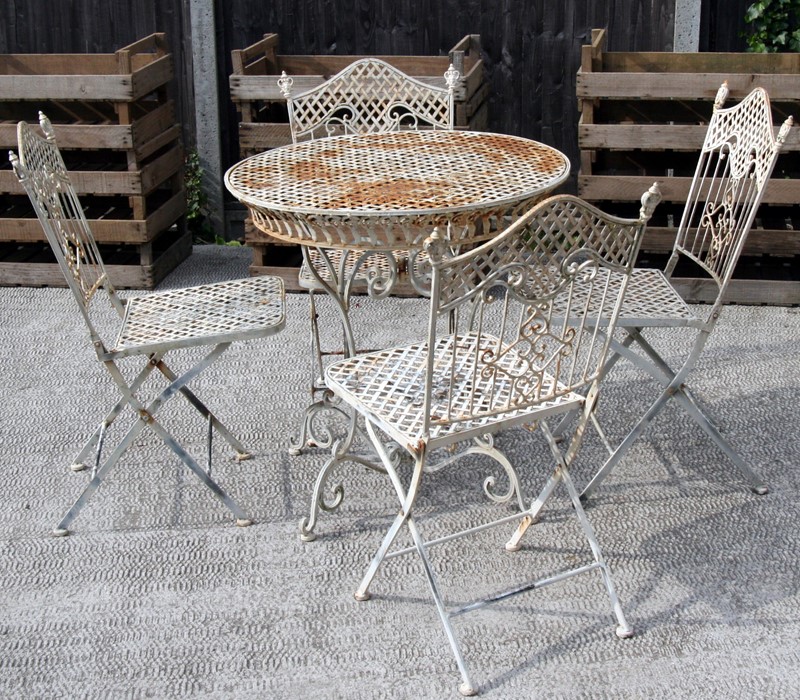 A cream painted metal garden set comprising a circular table and four folding chairs (5).