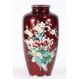 A Japanese cloisonne vase decorated with flowers on an oxblood ground, 24cms (9.5ins) high.