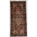 A Persian Hamadan woollen handmade runner with central medallion within a stylised border on a beige