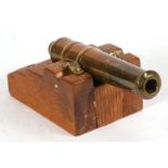 An early 20th century signal cannon with a brass barrel mounted on a wooden carriage. Barrel