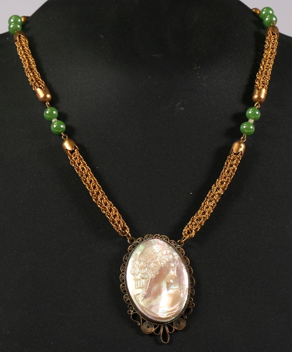 A filigree mounted mother of pearl cameo pendant on a gilt metal chain.