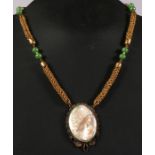 A filigree mounted mother of pearl cameo pendant on a gilt metal chain.