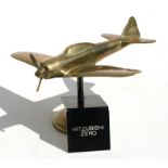 A brass model of the WW2 Japanese fighter the Mitzubishi Zero with spinning propeller standing on