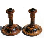 A pair of turned wood and brass candlesticks painted with far eastern peasants and figures on