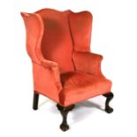 A pink upholstered wing back armchair on cabriole legs with ball & claw feet.