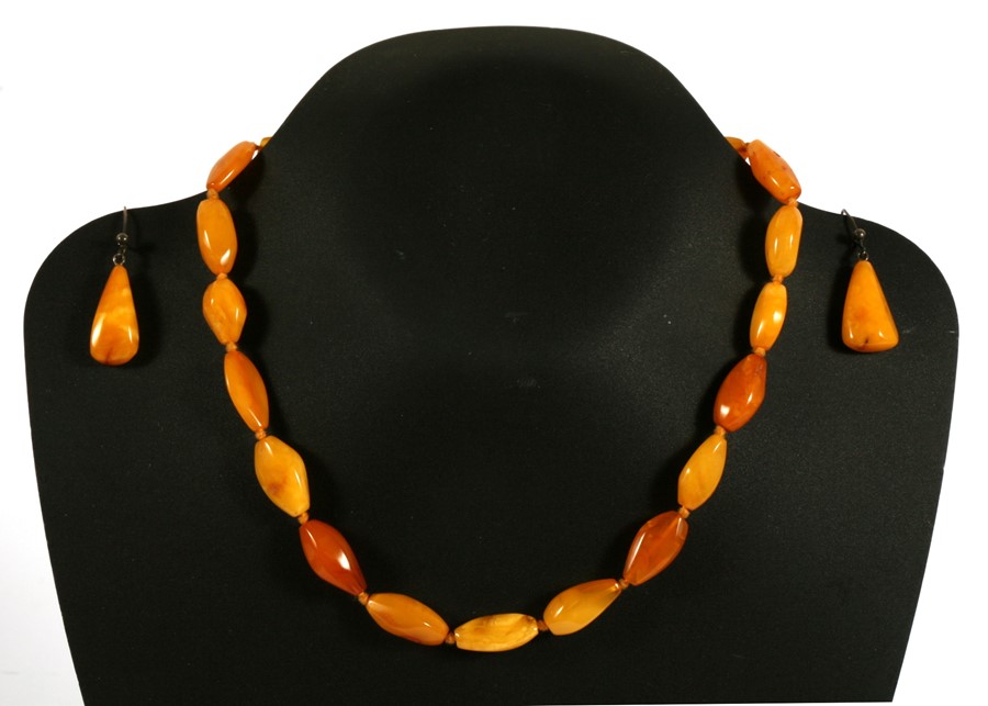 A butterscotch amber bead necklace; together with matching drop earrings, total weight 20g.
