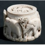 An early 20th century carved ivory box decorated in relief with elephants, 9cms (3.5ins) high.