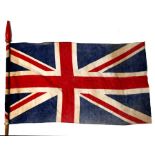 An early 20th century printed cotton Union Jack flag on its pole with finial. The flag is 42cms (