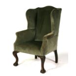 A wing back armchair on cabriole front supports with ball & claw feet.