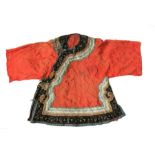 A Chinese silk embroidered short jacket decorated with a flower and butterfly border on a coral