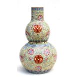 A Chinese famille rose double gourd vase decorated with foliate scrolls on a yellow ground, red seal