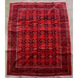 A Persian Balouch woollen handmade rug with geometric design on a red ground, 297 by 200cms (117