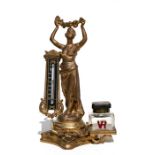 A Victorian gilt spelter figural table thermometer with single ink well, 24cms (9.5ins) high.