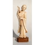 A late 19th / early 20th century carved ivory figure of Lohan carrying a bell and a fly whisk, 17cms
