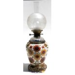 A Victorian oil lamp with ceramic body decorated with flowers, cut glass reservoir and gilt metal