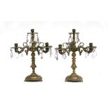 A pair of brass three-arm candelabra with crystal drops, 37cms (14.5ins) high.