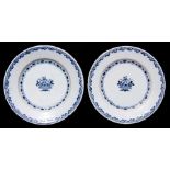 A pair of 18th century blue & white Delft plates decorated with a central vase with flowers,