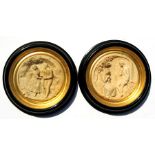 A pair of plaster relief plaques depicting courting couple in ebonised frames. 26cm (10.25 ins)