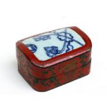 A Chinese lacquer box decorated with precious objects and foliate scrolls on a red ground with an