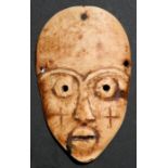 African / Tribal art - an early 20th century carved ivory plaque in the form of a face with