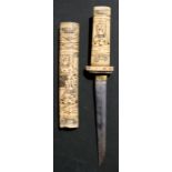 A Japanese carved bone Tanto dagger decorated with figures, 24cms (9.5ins) long.