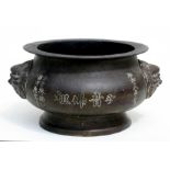 A Chinese bronze censer decorated with calligraphy and having two mask handles, 23cms (9ins)
