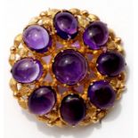 A 9ct gold brooch set with nine amethyst cabochons, 3cms (1.25ins) diameter.