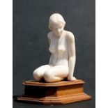 An Art Deco ivory figure in the form of a naked kneeling young lady, 7.5cms (3ins) high.