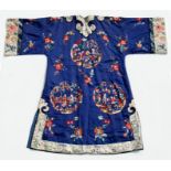 A Chinese silk embroidered long robe with panels depicting figures in garden settings, on a blue