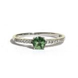 A 9ct white gold green Namibian demantoid ring with diamond set shoulders. Approx UK size N