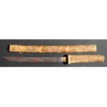 A Japanese carved bone short sword and scabbard decorated with figures, 56cms (22ins) long.