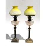 A pair of Victorian oil lamps with cut glass reservoirs, on Corinthian columns, with gilded brass