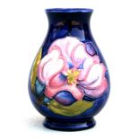 An unsigned Moorcroft vase decorated with pink flowers on a blue ground, 9.5cms (3.75ins) high.