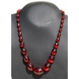 A faceted cherry amber Bakelite bead necklace, the largest bead 3cms, weight 46g.