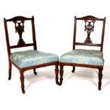 A pair of late 19th century walnut bedroom chairs with pierced splats and upholstered seats, on