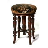 A late 19th century mahogany revolving piano stool on ring turned legs with upholstered seat.