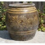 A large Chinese pottery plant pot decorated with dragons on a brown ground, 46cms (18ins) high.
