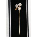 A French 18ct gold diamond and enamel stick pin in the form of a spray of daisies.