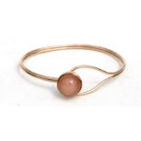 A 9ct gold bangle set with a hardstone cabochon, total weight 10.3g.