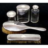 A silver part dressing table set to include clothes brush, hair brush and three silver mounted jars,