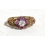 A 9ct gold ring with laurel leaf shoulders and central diamond surrounded by eight rubies, approx UK