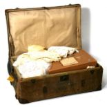 A canvas trunk containing a large quantity of linen items including tablecloths and children's